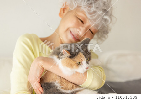 家で猫を抱っこする日本人シニア女性（猫・飼い主） 110315589