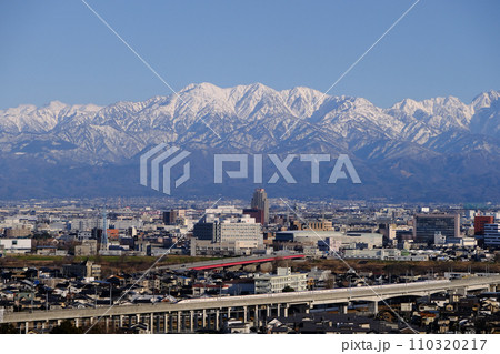 冬の北アルプス毛勝山望む北陸新幹線走る富山市街地2024.年1月5日撮影 110320217