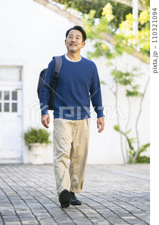 リュックを肩にかけて歩く中年男性　 110321094