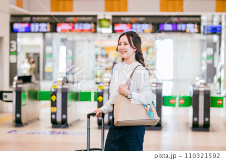 駅の改札でスーツケースを持った出張・旅行帰りの女性・ビジネスウーマン 駅の改札でスーツケースを持った出張・旅行帰りの女性・ビジネスウーマン 110321592