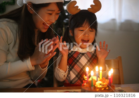 ローソクの火を吹き消す親子 110321816