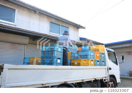男性がトラックの上で多数のコンテナを積み上げている 男性がトラックの上で多数のコンテナを積み上げている 110323307