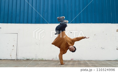Hispanic man stretch arms and dance street dancing in front of wall. Endeavor. 110324996