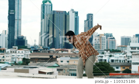 Hispanic break dancer practice B-boy footsteps at roof top with city. Endeavor. 110325186