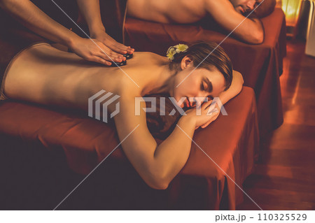Hot stone massage at spa salon in luxury resort with warm candle light.Quiescent Hot stone massage at spa salon in luxury resort with warm candle light.Quiescent 110325529