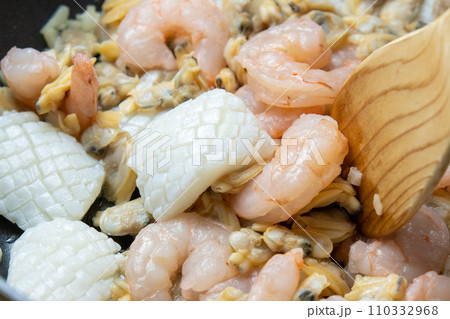 いかとえびとあさりをフライパンで炒める調理シーン。 110332968