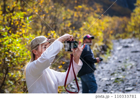 Girl taking pictures of mountain landscape Girl taking pictures of mountain landscape 110333781
