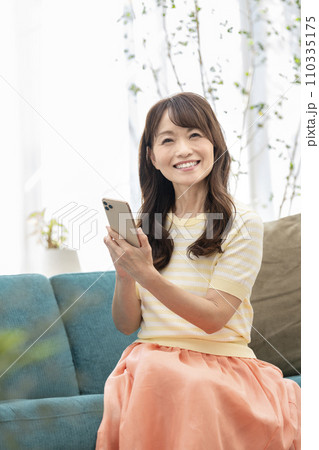 スマートフォンを持った笑顔の50代の女性 110335175