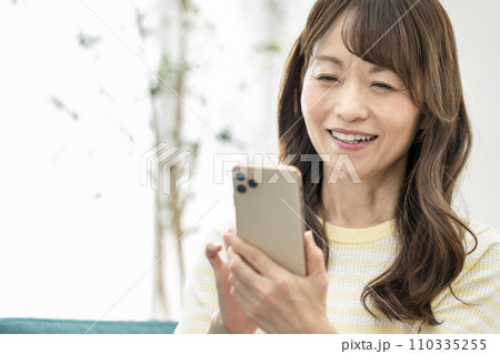 スマートフォンを操作する50代の女性 110335255