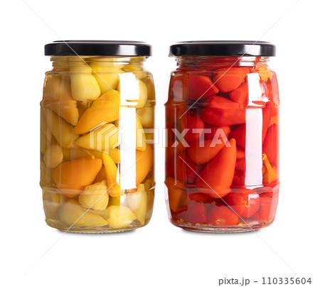Yellow and red hot baby peppers pickled in glass jars. Two glasses with small hot chilis or pepperonis, pasteurized and preserved in a brine of water, vinegar and salt. Close-up, front view. Photo. 110335604