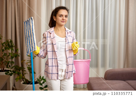 happy woman cleaning floor at living room, girl holding bucket and mop, daily housekeeping 110335771