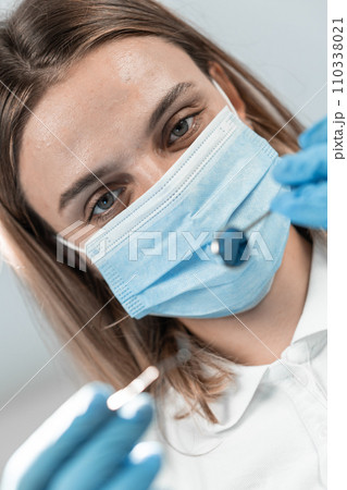 A professional dentist in her dental office is image of real expert who combines warmth and confidence. With attention to detail and a smile, she guides her patients through every stage of treatment. 110338021