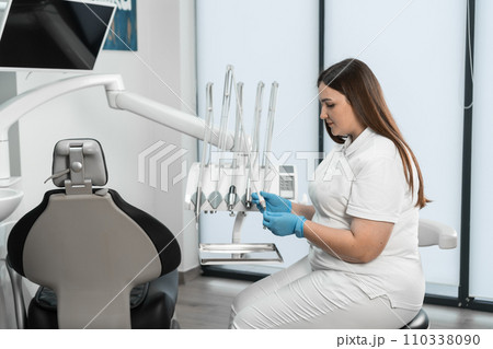 A dentist in her dental office expresses professionalism and attention to detail, ready to provide quality dental care. 110338090