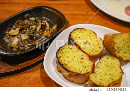 都会のイタリアンレストランやスペイン料理で食べるガーリックトーストとキノコのアヒージョ（東京都） 110339031