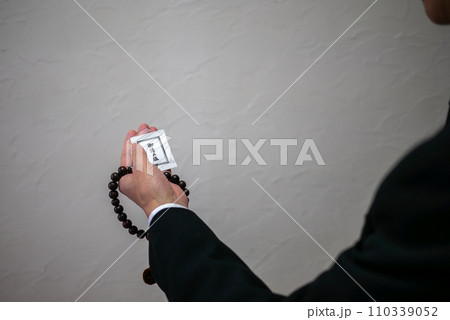 数珠とお清めの塩を持った男性の手元 110339052