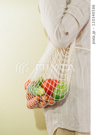 different vegetables in the shopping bag that hangs on the girl's shoulder 110340586