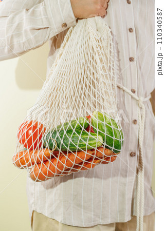 different vegetables in the shopping bag that hangs on the girl's shoulder 110340587
