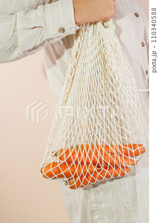 fresh carrots in a shopping bag that hangs on the girl's shoulder 110340588