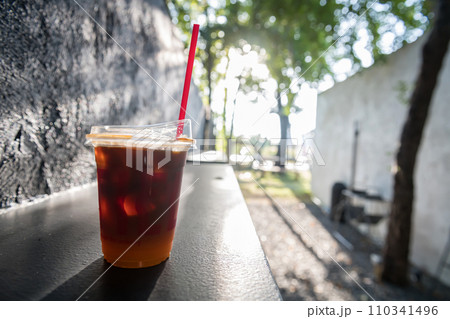 Iced black americano coffee with yuzu juice in glass at outdoor cafe Iced black americano coffee with yuzu juice in glass at outdoor cafe 110341496