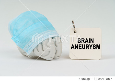 On a white surface next to the brain there is a notepad with the inscription - Brain aneurysm 110341867