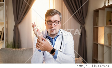 Pulse monitoring. Doctor blog. Online instructions. Physician man in medical uniform measuring heart rate by hand at wrist for video channel in modern hospital office interior. 110342923