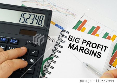 On the table there is a calculator, reports with graphs and a notepad with the inscription - Big Profit Margins 110342944