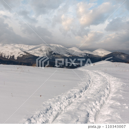 Sledge trace and footprints on winter mountain hill top 110343007