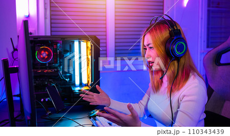Game over you lose. Angry Asian gamer wearing gaming headphones playing joystick console video game on computer PC neon light at home feeling sad disappointed about game losing, player unhappy E-Sport 110343439