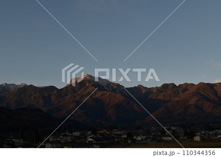 山麓に朝日が当たる南アルプス甲斐駒ケ岳と日の出前の白州の街並み 110344356