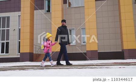 girl holding her father hand, school road education classes, concept happy family, little child kid daughter with school backpack walking through snow boots, school student with backpack, daughter bag 110344617