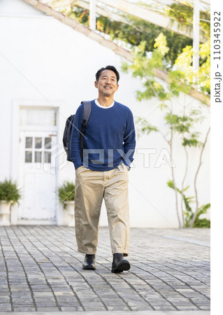 リュックを肩にかけて歩く50代半ばの男性 リュックを肩にかけて歩く50代半ばの男性 110345922
