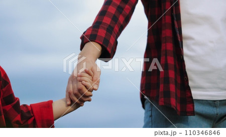 Agriculturist child holds mother hand among maize plantation against cloudy sky Agriculturist child holds mother hand among maize plantation against cloudy sky 110346846