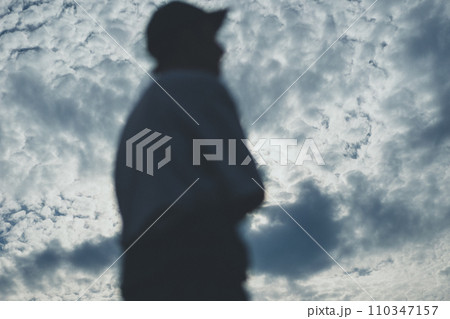 つなぎを半分脱いだ若い男性と青空 つなぎを半分脱いだ若い男性と青空 110347157