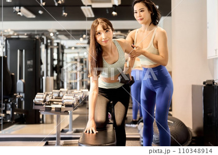 ワンハンドダンベルロウで背中と腕を鍛える女性 110348914