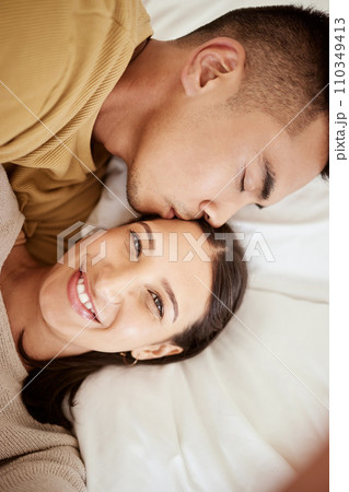 Happy, smiling and affectionate young couple in love taking a selfie together in the bed at home. Portrait of loving female taking a photo in happiness while her partner is sleeping during the day. Happy, smiling and affectionate young couple in love taking a selfie together in the bed at home. Portrait of loving female taking a photo in happiness while her partner is sleeping during the day. 110349413