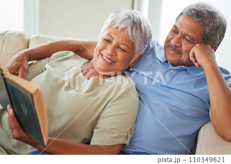 Relax, happy and senior couple reading a book together at home while relaxing and smiling on a couch. Mature or old lovers learning and resting while enjoying a story as entertainment in the house Relax, happy and senior couple reading a book together at home while relaxing and smiling on a couch. Mature or old lovers learning and resting while enjoying a story as entertainment in the house 110349621