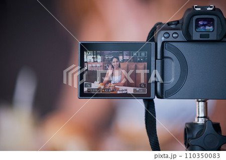 Woman influencer on digital camera screen recording vlog for online social media video. Creative young female content creator presenting internet or web content for her website or podcast at a cafe 110350083
