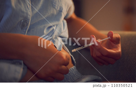Diabetes, diabetic and insulin injection of a woman with a chronic disease late at night. Hands of a female taking her daily shot of treatment with a syringe in the evening at home 110350521
