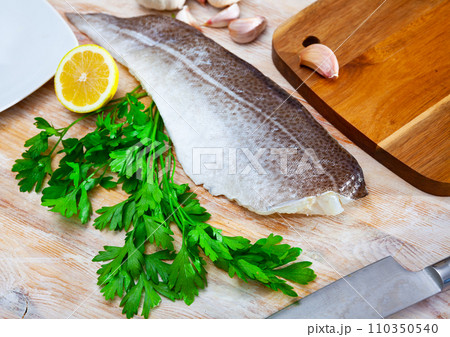 Raw cod fillet with garlic and lemon on wooden surface 110350540