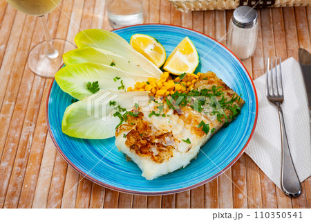 Pink cusk-eel fillet with endive, pickled corn, lemon and greens 110350541