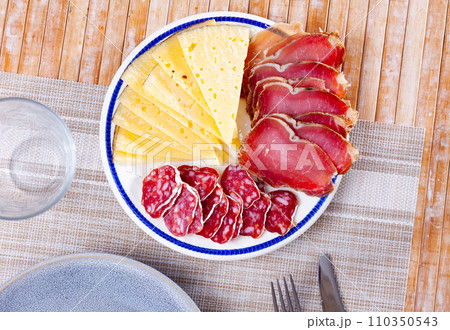 Circles of sausage butifarra, slices of prosciutto ham are complemented by triangular sliced cheese 110350543