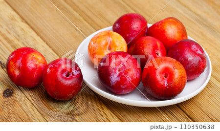 Sweet red plums on wooden table 110350638