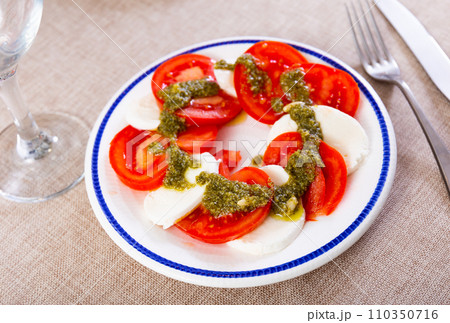 Traditional snack of Italian cuisine is Caprese with basil and Pesto sauce closeup Traditional snack of Italian cuisine is Caprese with basil and Pesto sauce closeup 110350716