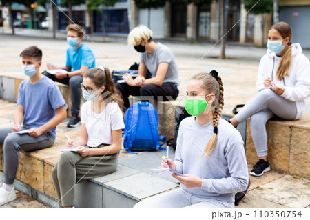 Focused teen students in masks during lesson outside 110350754