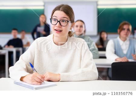 Female student sit at desk and makes notes Female student sit at desk and makes notes 110350776
