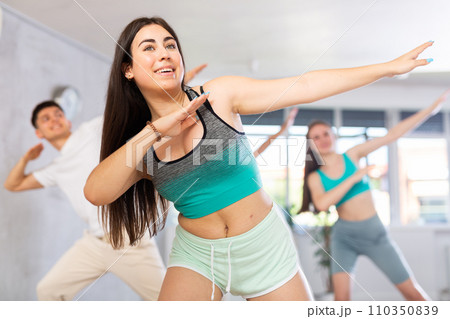 Cheerful hispanic teenage girl showcasing dabbing move during dance class 110350839