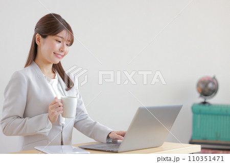 コーヒーカップを持ちタイピングするビジネスウーマン1 110351471