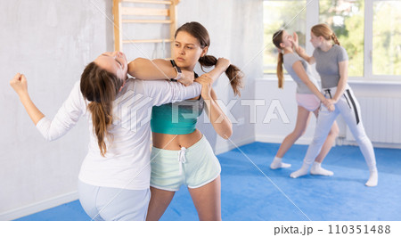 Girl and woman athletes in pair conduct training battle in oriental fighting technique Girl and woman athletes in pair conduct training battle in oriental fighting technique 110351488