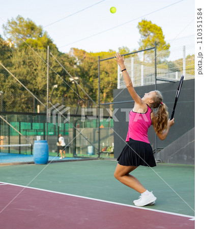 Young woman in skirt playing tennis on court Young woman in skirt playing tennis on court 110351584