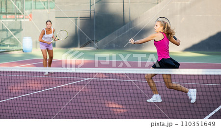 Caucasian woman wearing in pink t-shirt and skirt playing tennis match during training 110351649